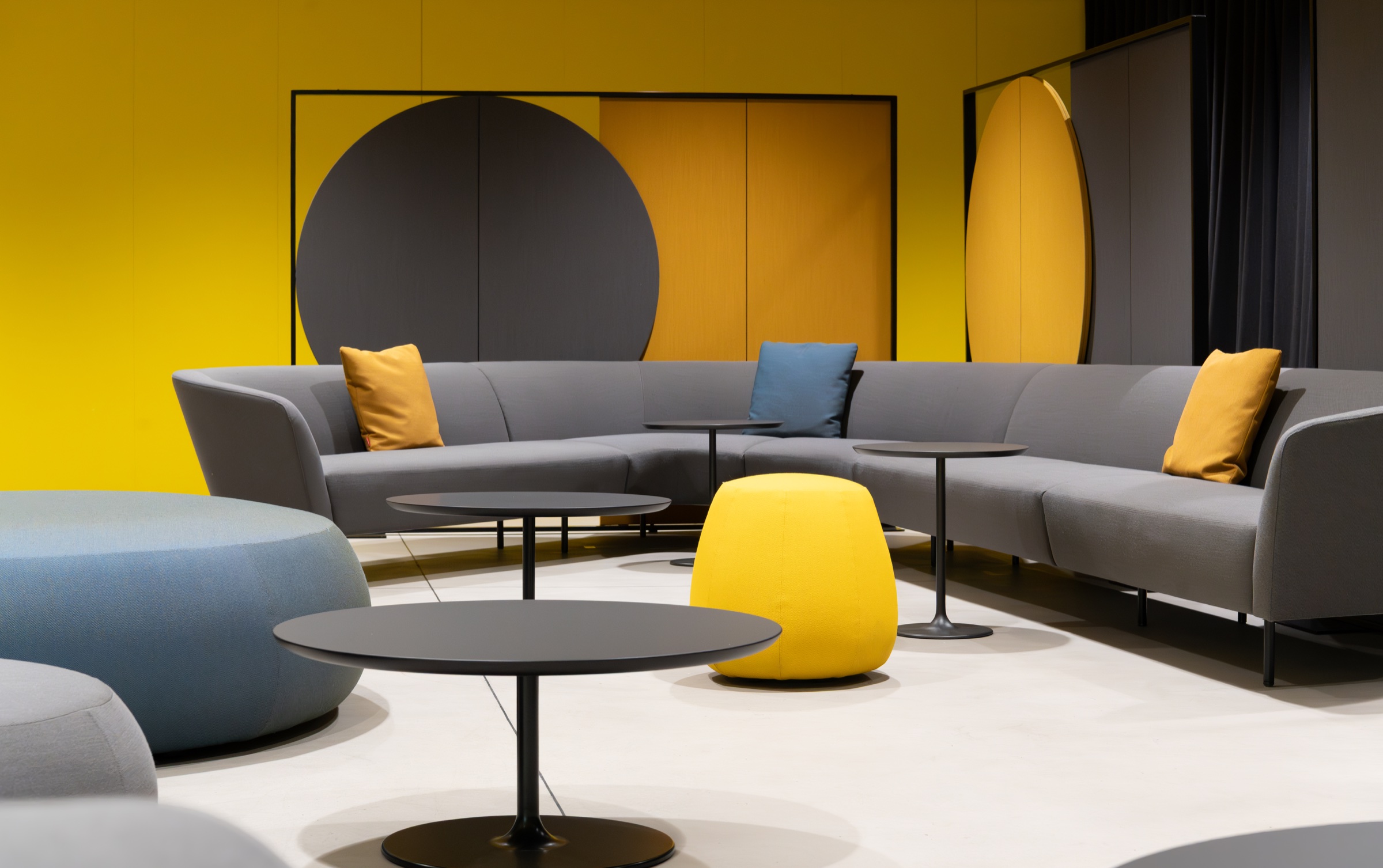 VIP Lounge mit grauer Sitzlandschaft, gelben Akzenten und grafischen Wandelementen