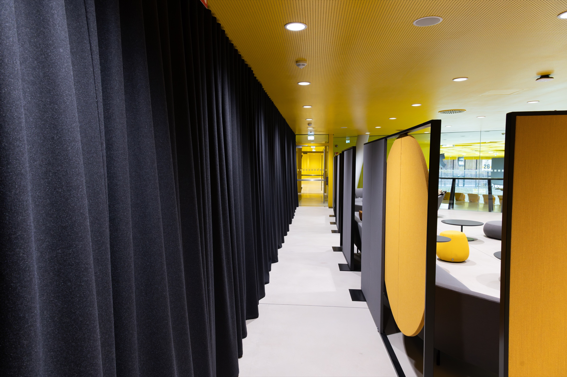 Blickachse durch die VIP Lounge mit schwarzen Vorhängen und gelben Einbauten